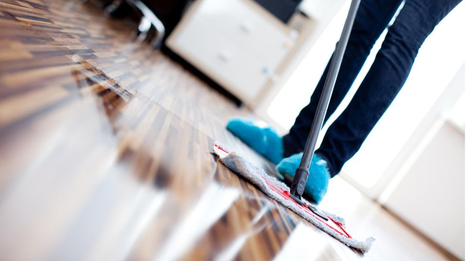 Parkett reinigen: Frau pflegt Holzboden mit einem Wischmopp