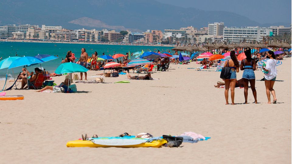 Menschen sonnen sich und schwimmen am Strand von Arenal auf Mallorca