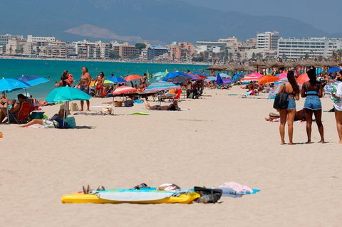Menschen sonnen sich und schwimmen am Strand von Arenal auf Mallorca