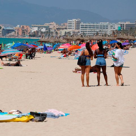 Menschen sonnen sich und schwimmen am Strand von Arenal auf Mallorca
