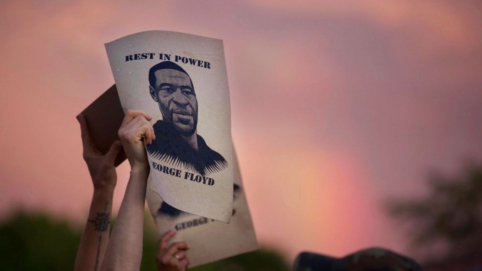 Demonstranten halten während eines Protestes Zettel mit dem Porträt von George Floyd