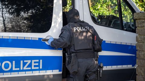 Nordrhein-Westfalen: Ein Polizist steht im Rahmen einer Razzia an einem Polizeifahrzeug