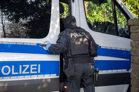 Nordrhein-Westfalen: Ein Polizist steht im Rahmen einer Razzia an einem Polizeifahrzeug