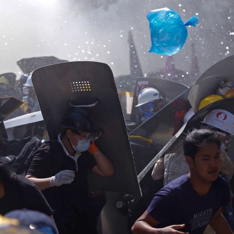 Menschen werden während eines Protests gegen den Putsch der Militärjunta auf einer Straße von der Polizei mit Tränengas auseinander getrieben