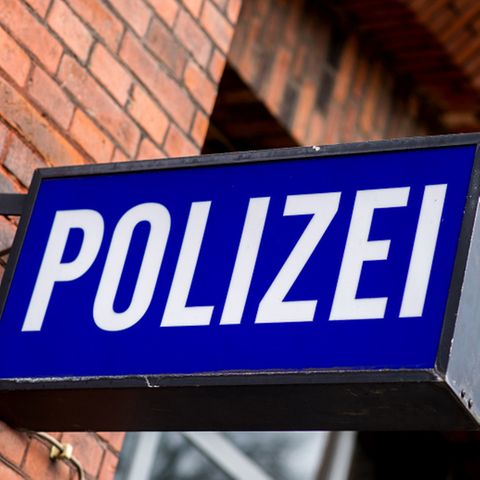 Ein blaues Polizeischild vor einer roten Ziegelwand