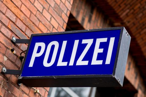 Ein blaues Polizeischild vor einer roten Ziegelwand