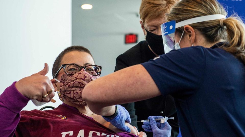 Eine Frau zeigt Damen hoch während sie in Connecticut gegen Corona geimpft wird