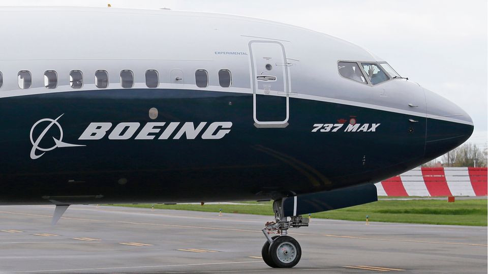 Aus der Kanzel einer blau-weiß lackierten Boeing 737-Max winkt ein Pilot durch die geschlossenen Fenster