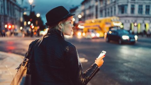 Eine Frau, nachts auf dem Nachhauseweg, Handy in der Hand
