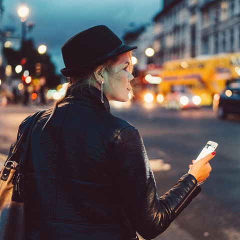 Eine Frau, nachts auf dem Nachhauseweg, Handy in der Hand