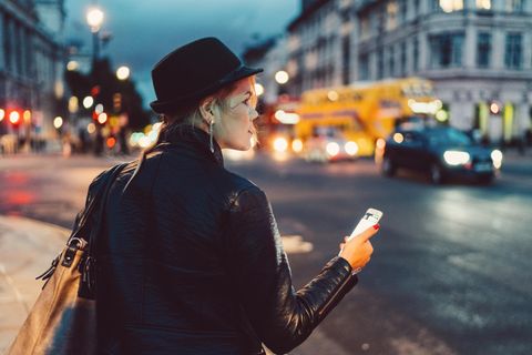 Eine Frau, nachts auf dem Nachhauseweg, Handy in der Hand