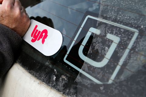 Ein Lyft-Logo ist auf dem Auto eines Lyft-Fahrers neben einem Uber-Aufkleber angebracht