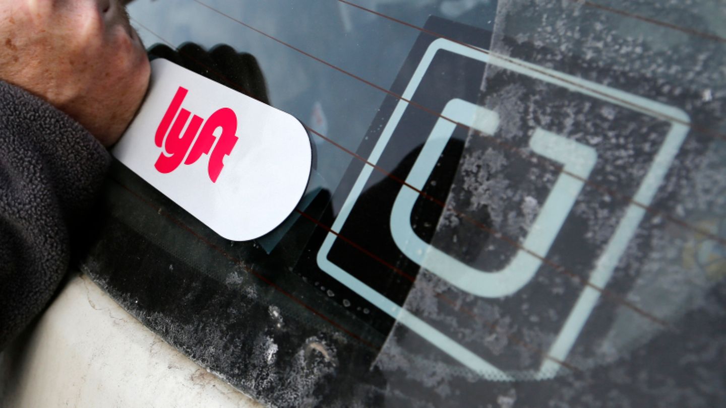 Ein Lyft-Logo ist auf dem Auto eines Lyft-Fahrers neben einem Uber-Aufkleber angebracht