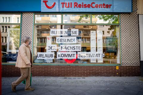 Eine Passantin mit Maske geht an einem Reisebüro vorbei