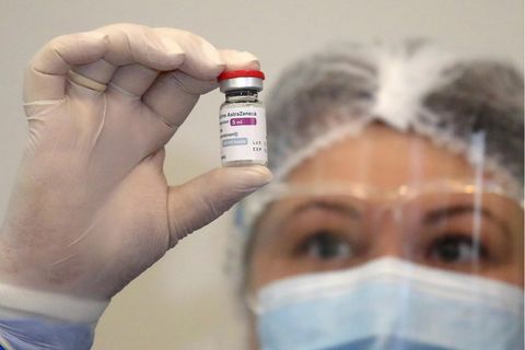 Eine Frau hält eine Ampulle mit dem Impfstoff von Astrazeneca in die Kamera