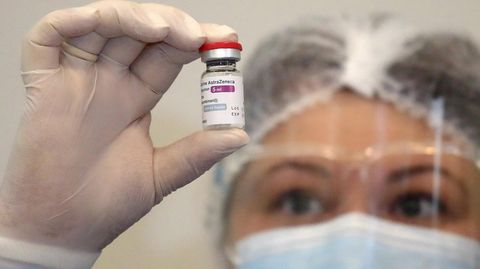 Eine Frau hält eine Ampulle mit dem Impfstoff von Astrazeneca in die Kamera