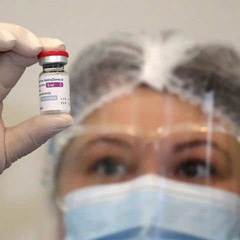 Eine Frau hält eine Ampulle mit dem Impfstoff von Astrazeneca in die Kamera