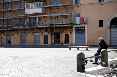 Ein Mann sitzt auf dem fast menschenleeren Navona-Platz in Rom