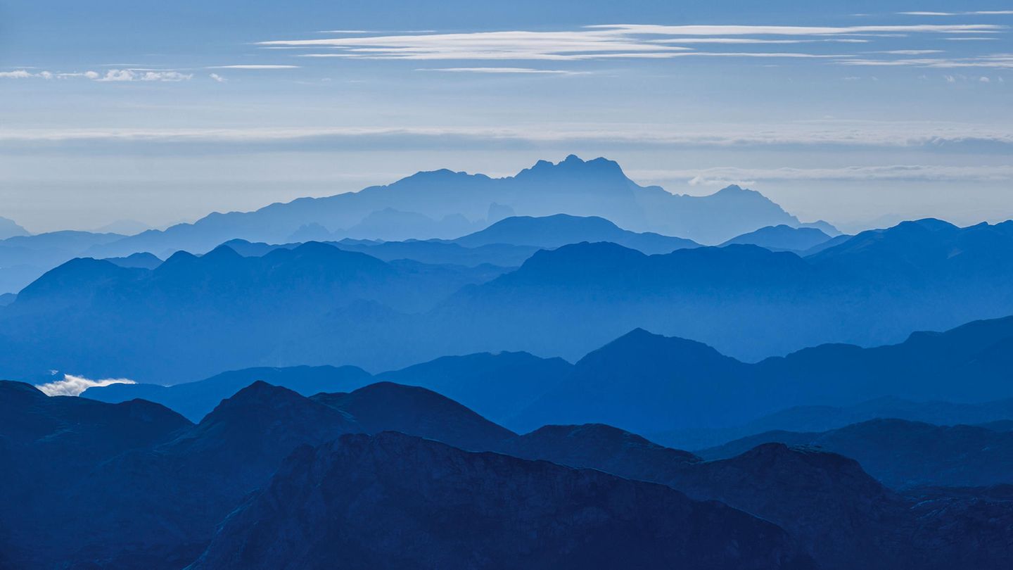 Ein klarer Sommermorgen auf dem Watzmann Hocheck. In der Ferne leuchtet blau aus dem morgendlichen Dunst der Hohe Dachstein. Knesebeck