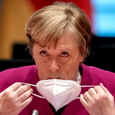 Angela Merkel nimmt sich ihren Mund-Nasen-Schutz ab