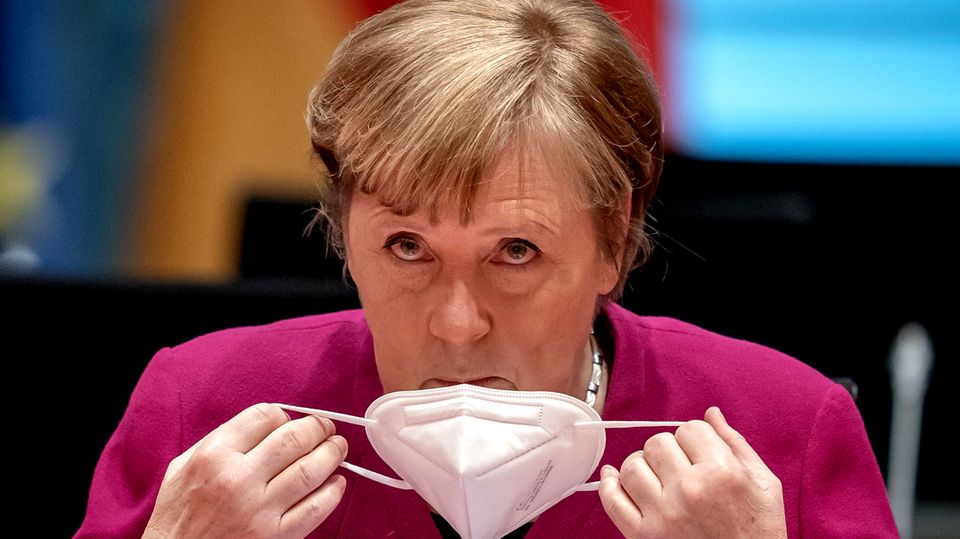 Angela Merkel nimmt sich ihren Mund-Nasen-Schutz ab