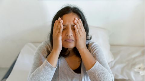 Eine Frau hält sich ihre Hände an die Schläfen und Wangen