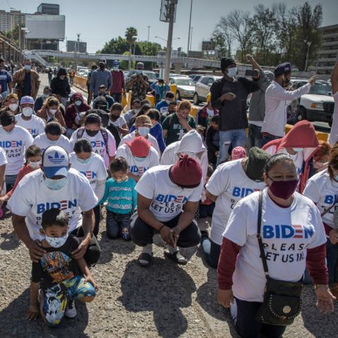 Eine Gruppe Migranten kniet am US-Grenzübergang und betet. Auf ihren T-Shirts steht: "Biden, lass uns bitte rein"
