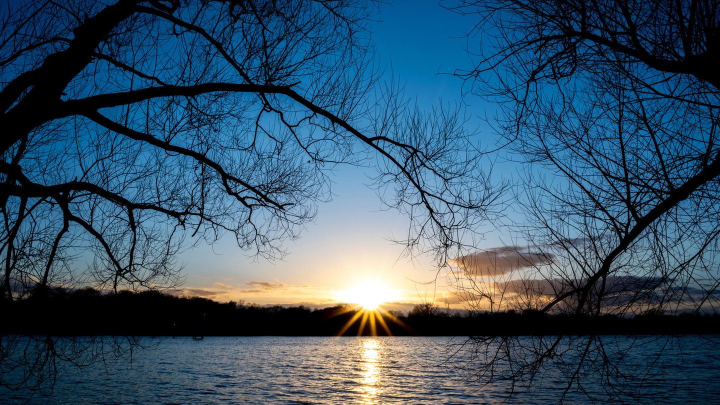 Die Sonne geht hinter Bäumen am Maschsee unter