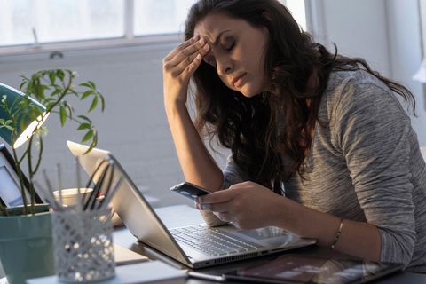 Geschäftsfrau schaut frustriert auf Smartphone und Laptop