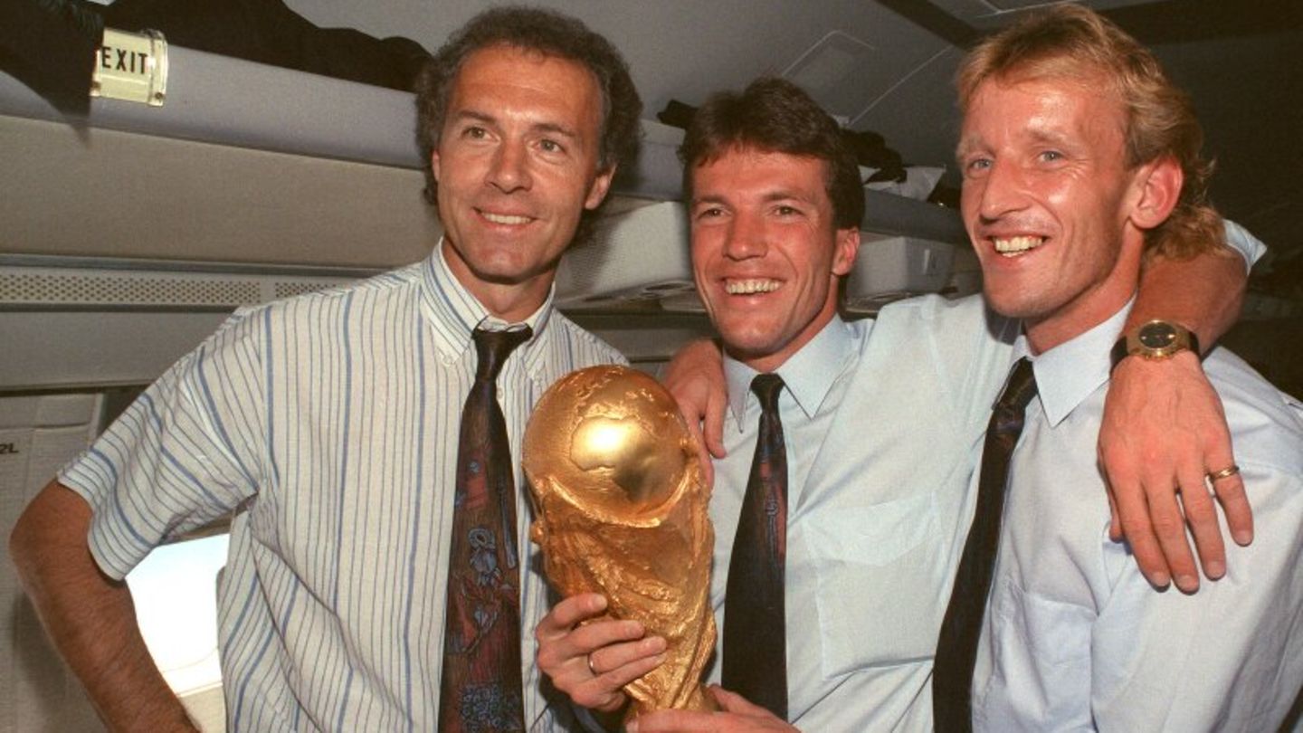 Franz Beckenbauer, Lothar Matthäus und Andreas Brehme posieren mit Weltmeisterschaftspokal.
