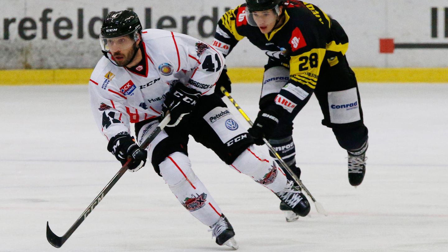 Die Crocodiles Hamburg spielen in der Oberliga Nord, der dritthöchsten deutschen Spielklasse im Eishockeysport. Das Bild zeigt einen Zweikampf zwischen Michael Bezouska (Crocodiles Hamburg) und Adam Kiedewicz (Krefelder SV) in der Saison 2020/2021.