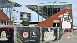 Die Graffiti an den Wänden des Millerntors heben es optisch von den anderen Fußballstadien ab. Im Bild rechts ist mit der Spielanzeige in der Hand die Figur des Künstlers "Rebelzer" zu sehen.