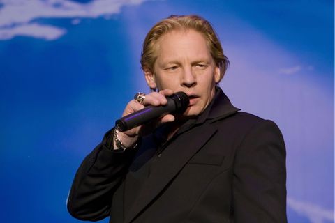 Ben Becker steht bei einer Lesung auf der Bühne und hält das Mikrofon