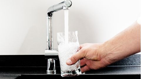 Zum Weltwassertag: Trinkwasser fließt aus einem Wasserhahn in ein Glas