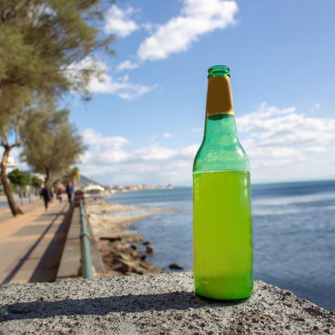 Ein Flasche Bier steht an einem Gewässer
