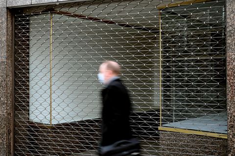 Mann mit Mundschutz geht an einem geschlossenen Geschäft vorbei.