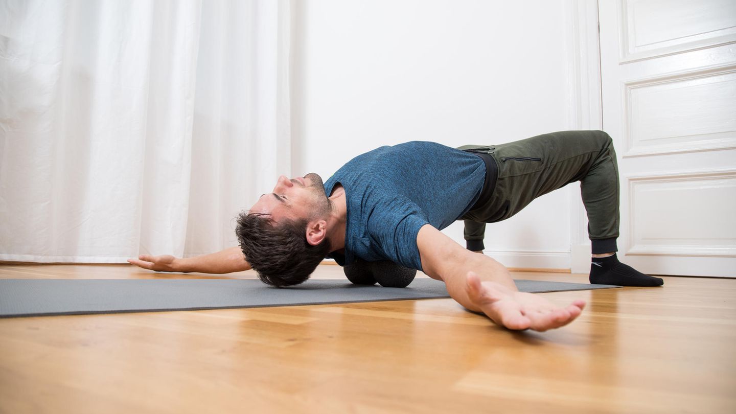 Triggerpunktmassage: Mann liegt mit zwei Massagebällen im Rücken auf eine Gymnastikmatte