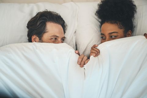 Penisring: Ein Pärchen liegt im Bett und schaut sich in die Augen.