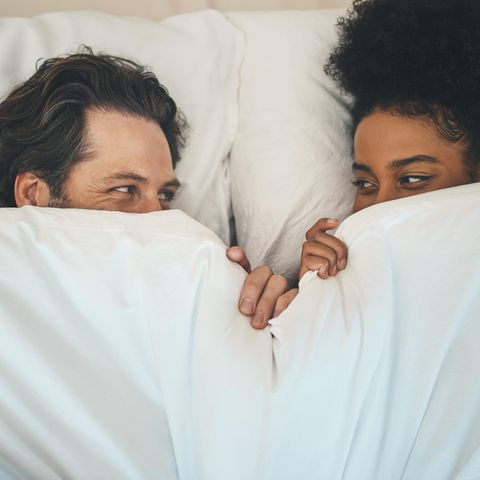 Penisring: Ein Pärchen liegt im Bett und schaut sich in die Augen.