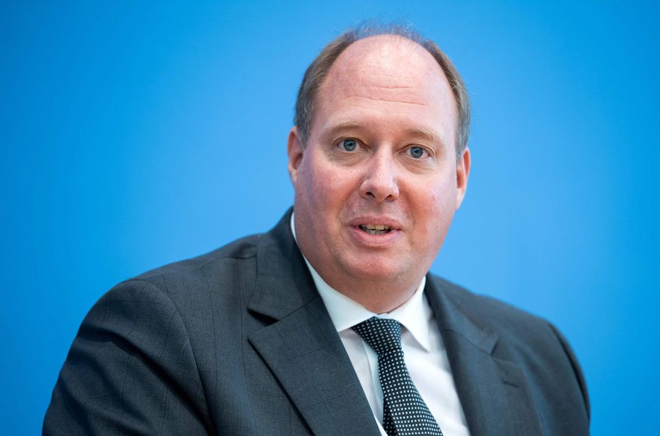 Helge Braun Ein beleibter Mann mit Halbglatze sitzt in Anzug und Krawatte vor einem blauen Hintergrund