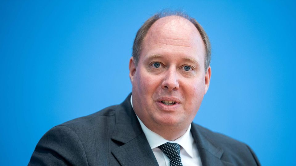 Helge Braun Ein beleibter Mann mit Halbglatze sitzt in Anzug und Krawatte vor einem blauen Hintergrund
