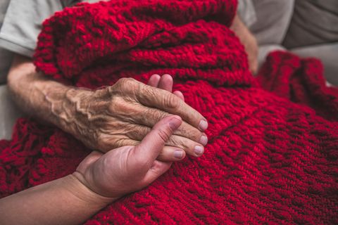 Krankenschwester in einem Hospiz hält einem Sterbenden die Hand