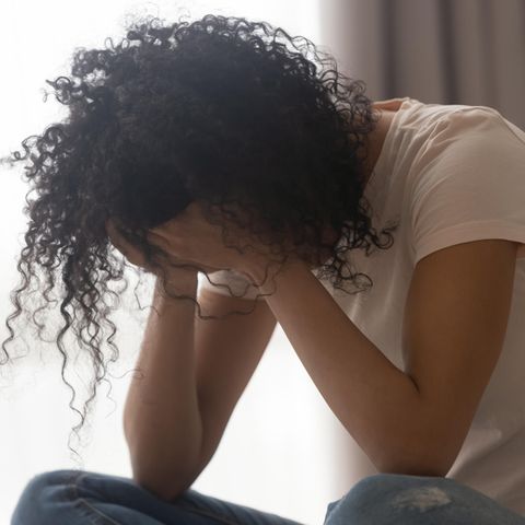 Eine trauernde Frau sitzt auf dem Bett