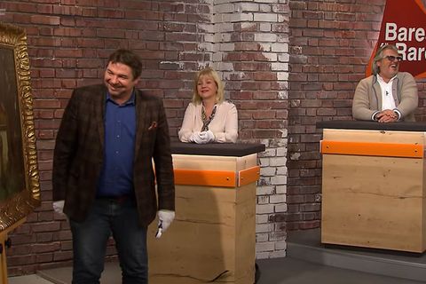 Daniel Meyer steht im Bares für Rares Händlerraum, Elke Velten-Tönnies und Roman Runkel sitzen daneben