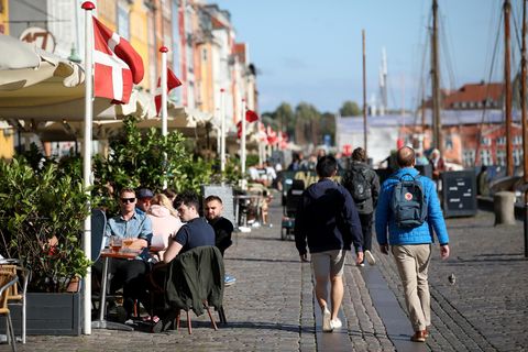 Menschen sitzen draußen in Restaurants und Cafés in Nyhavn, Kopenhagen