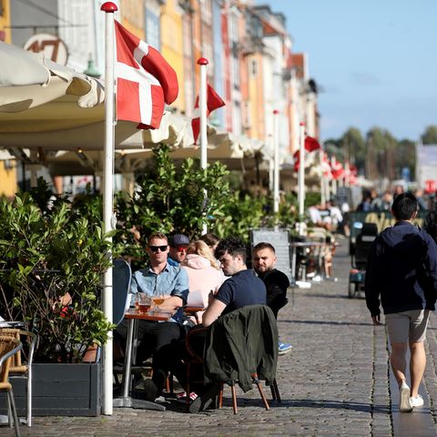 Menschen sitzen draußen in Restaurants und Cafés in Nyhavn, Kopenhagen
