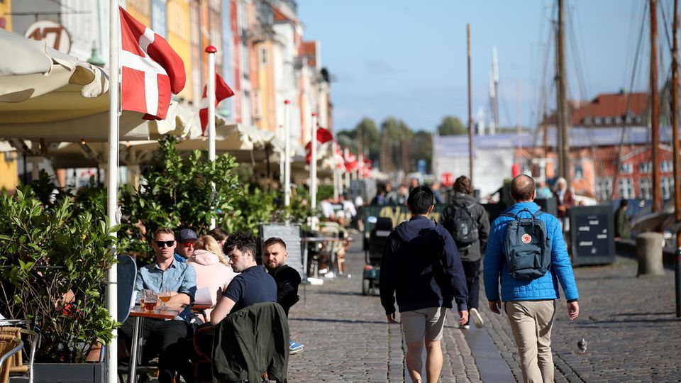 Menschen sitzen draußen in Restaurants und Cafés in Nyhavn, Kopenhagen