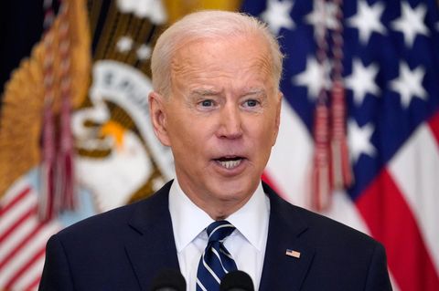 US-Präsident Joe Biden spricht, während hinter ihm unscharf US-Flaggen zu sehen sind