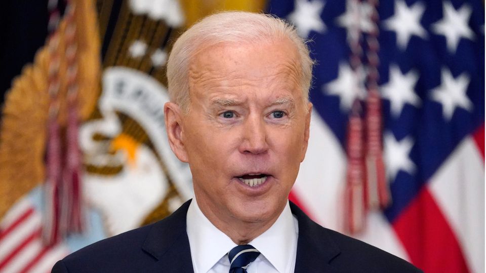 US-Präsident Joe Biden spricht, während hinter ihm unscharf US-Flaggen zu sehen sind