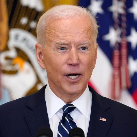 US-Präsident Joe Biden spricht, während hinter ihm unscharf US-Flaggen zu sehen sind
